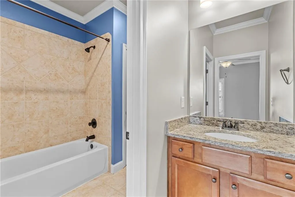 Full bath featuring ornamental molding, shower / bath combination, vanity, and light tile patterned floors