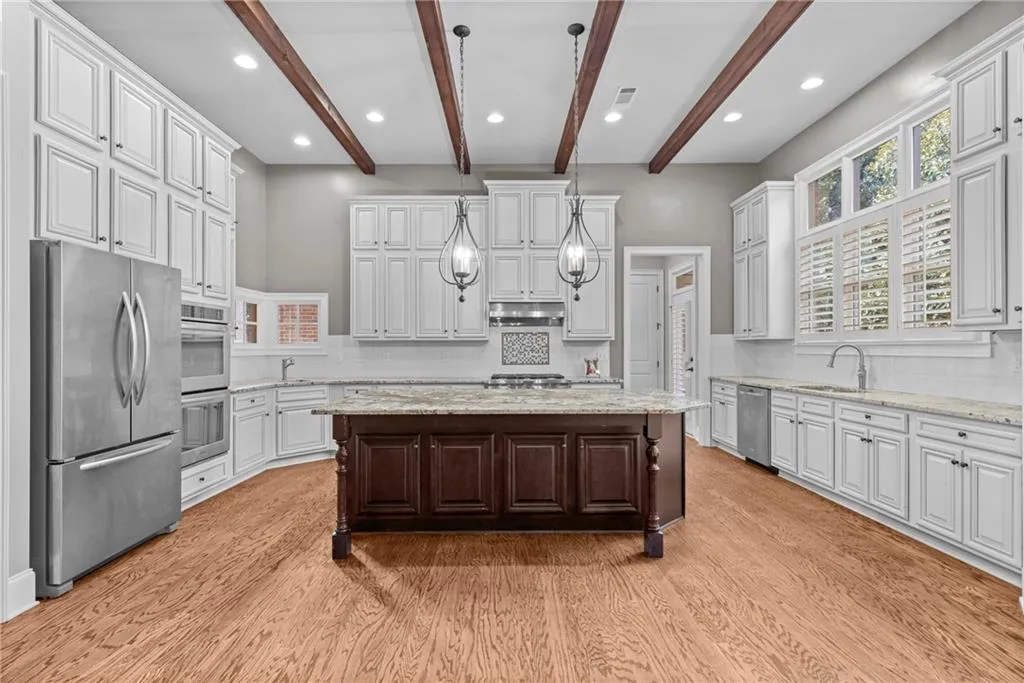 Kitchen with dark brown cabinetry, stainless steel appliances, light stone counters, a center island, and recessed lighting