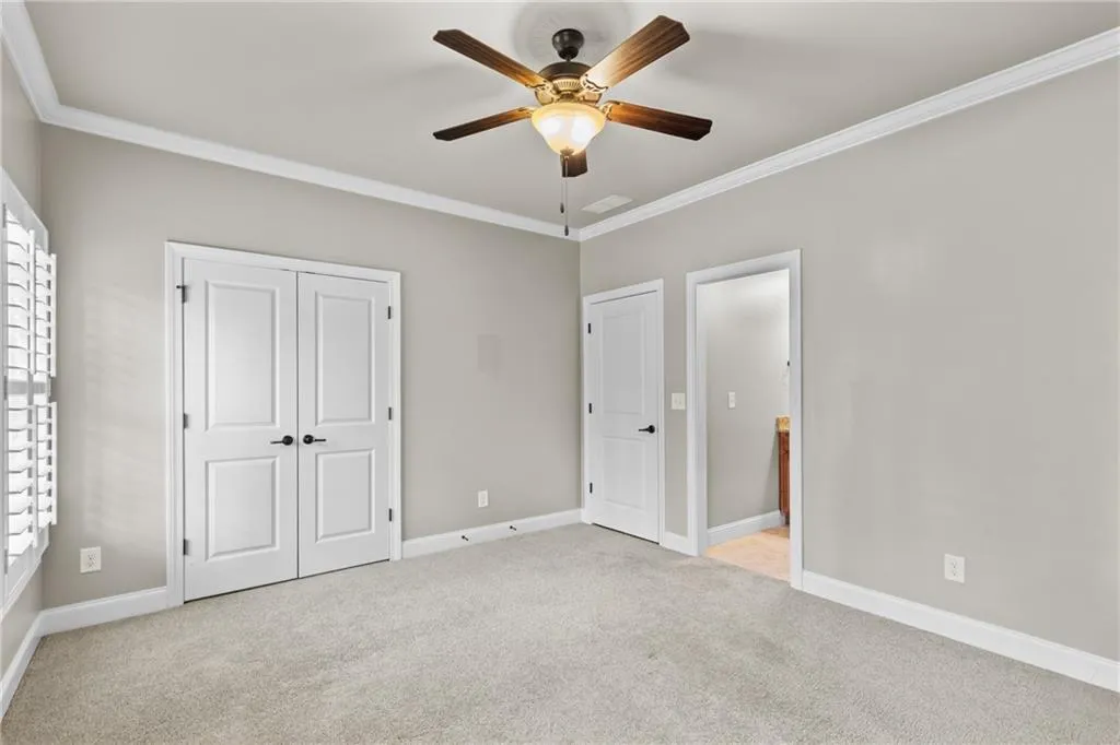 Unfurnished bedroom with crown molding, light colored carpet, a ceiling fan, and a closet