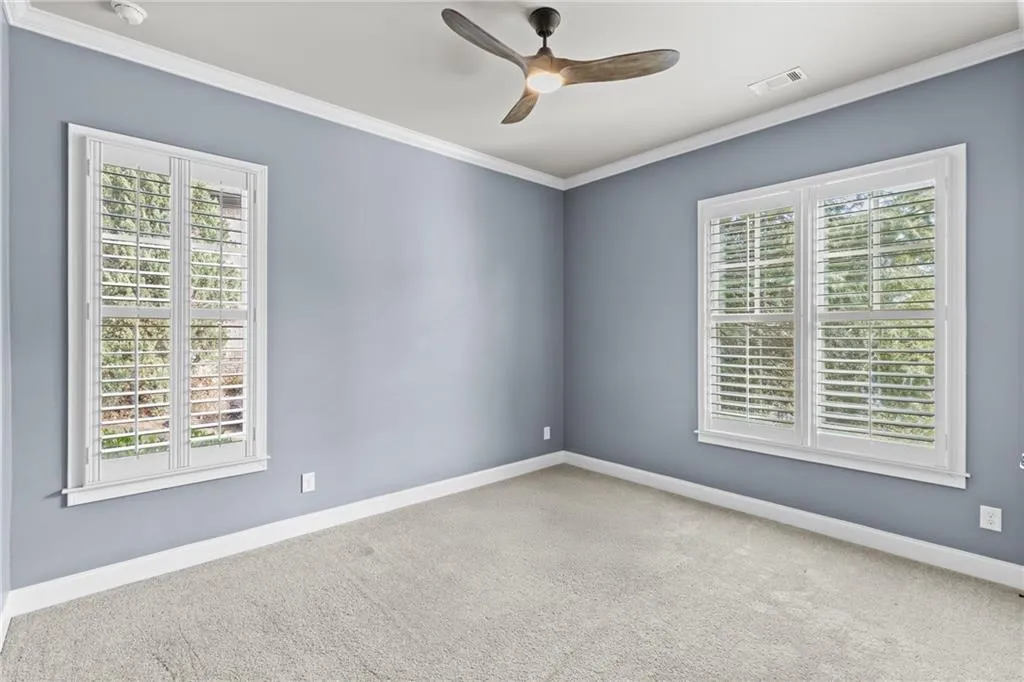 Empty room featuring crown molding, a ceiling fan, and carpet flooring