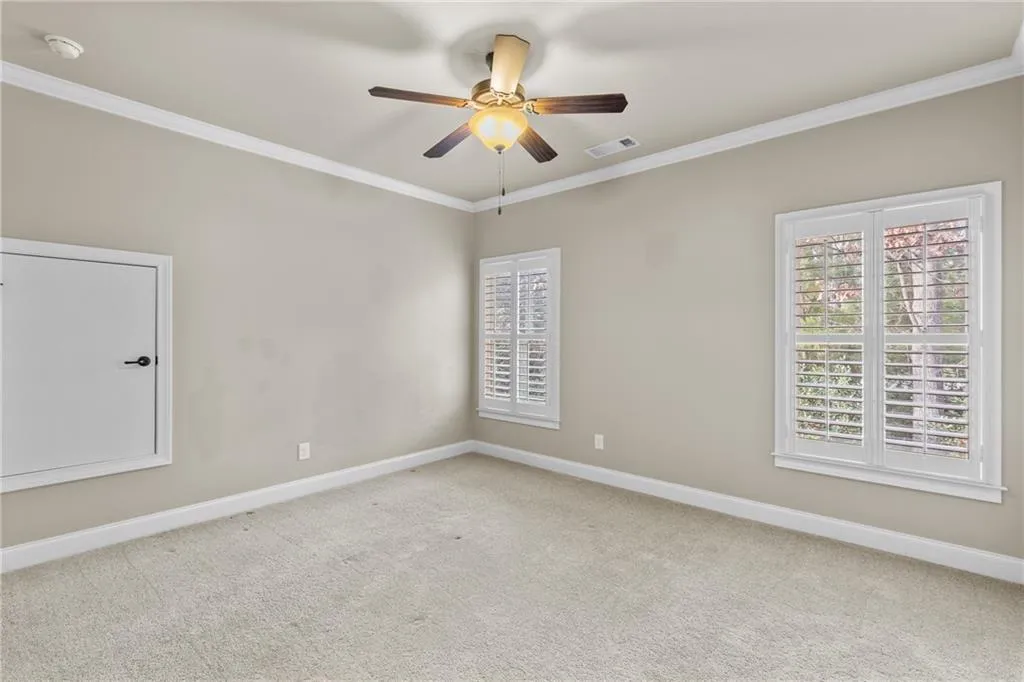 Spare room featuring ornamental molding, light colored carpet, and a ceiling fan