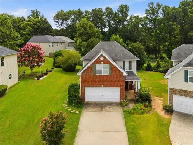 Two-story property featuring a brick and siding facade, a two-car garage, and a covered front porch with white columns