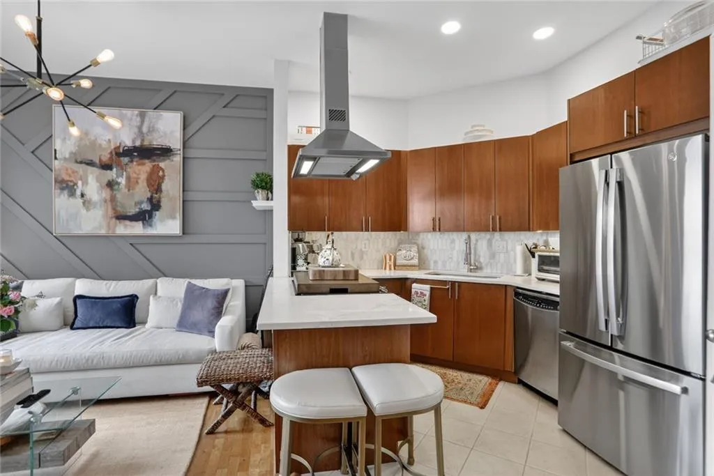 Stylish kitchen featuring stainless steel appliances, rich cabinetry, quartz countertop and marble backsplash.