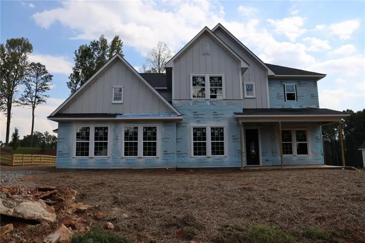 Two-story residence with a covered front entry, multiple gabled rooflines, and a visible building wrap