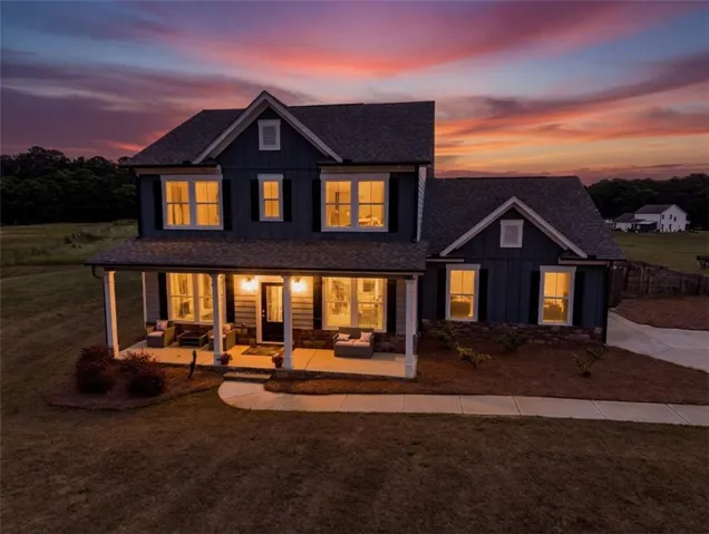 Two-story residence featuring a covered front porch, dark siding, and a gabled roofline