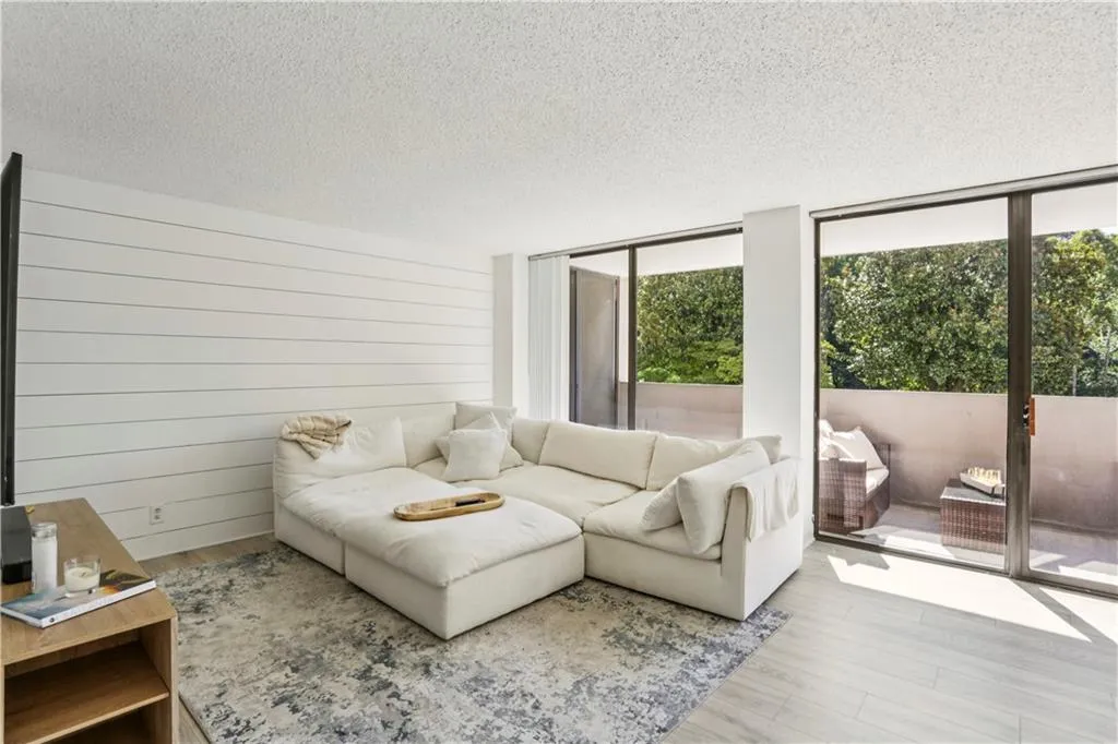 Living room with a textured ceiling, wood finished floors, floor to ceiling windows, and wood walls