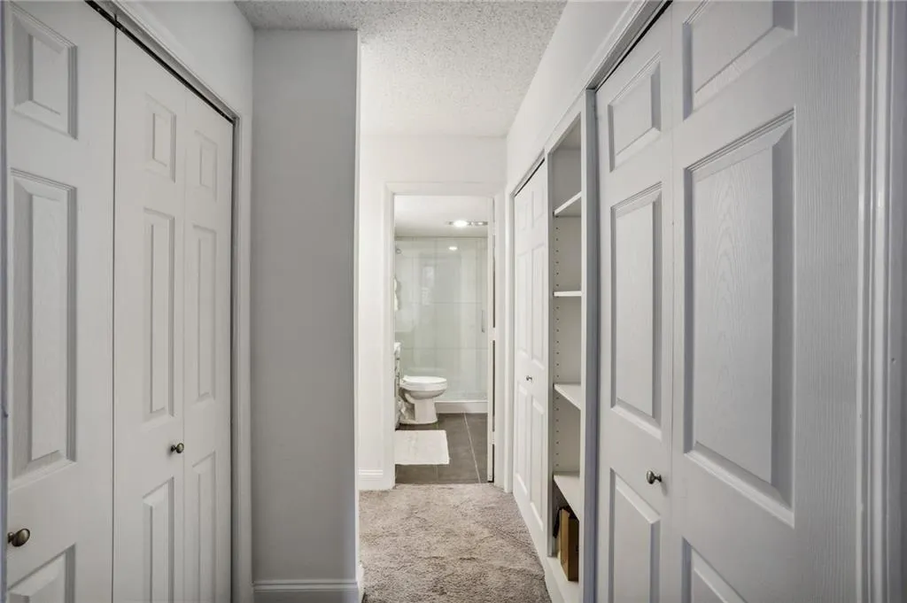 Corridor to Primary Bathroom. 3 reach in closets, shelving and open alcove for dresser.