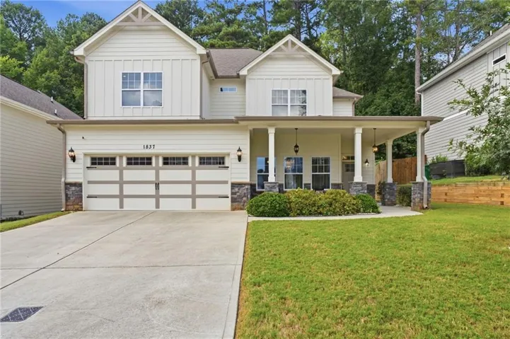 Two-story residence featuring light-colored siding, a covered front porch, and a two-car garage with decorative hardware
