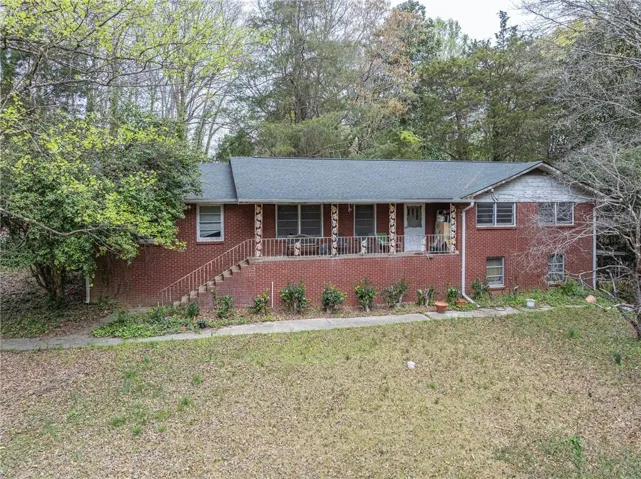 Ranch-style home with covered porch, a front lawn, and brick siding