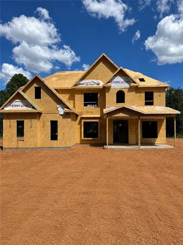 Expansive two-story home under construction featuring multiple gabled rooflines, a welcoming covered front porch, and numerous window openings