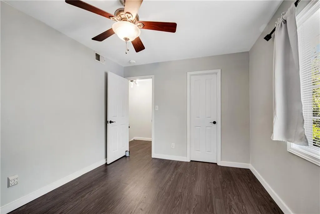 Unfurnished bedroom featuring dark hardwood / wood-style flooring and ceiling fan