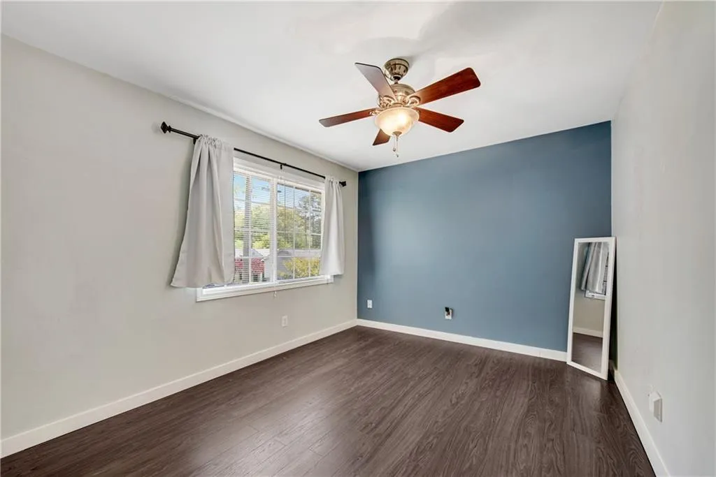 Empty room with dark hardwood / wood-style flooring and ceiling fan