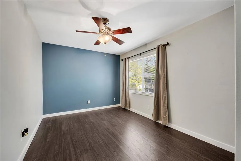 Empty room with ceiling fan and dark wood-type flooring