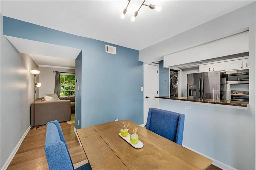 Dining space featuring light hardwood / wood-style floors, crown molding, and stacked washer / drying machine