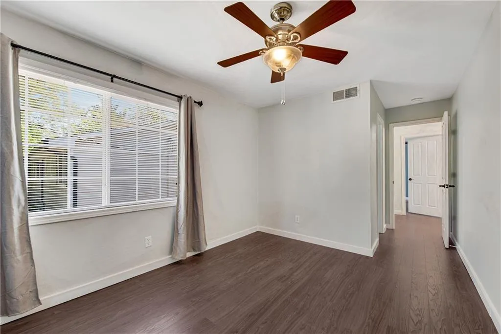 Empty room featuring dark wood-type flooring and ceiling fan