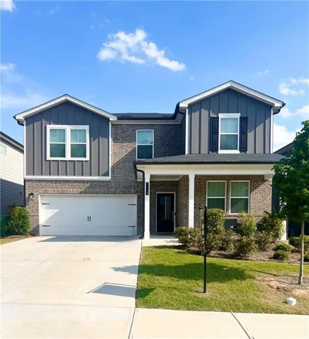 Two-story residence featuring a brick and vertical siding facade, an attached two-car garage, a covered front porch with white columns, and a concrete driveway
