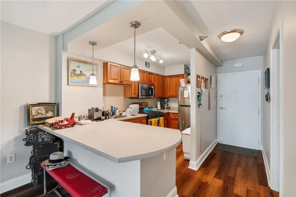 Kitchen with kitchen peninsula, stainless steel appliances, pendant lighting, dark hardwood / wood-style flooring, and a breakfast bar area