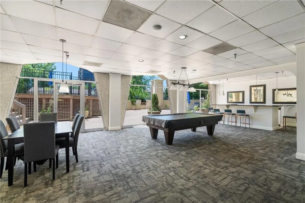 Rec room with dark carpet, a wall of windows, pool table, and a drop ceiling