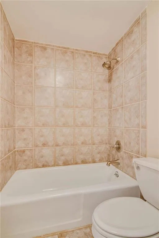 Bathroom with tiled shower / bath combo and toilet