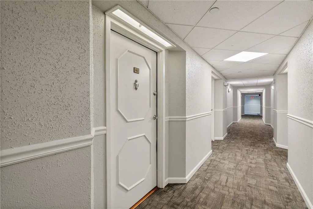 Corridor with carpet flooring and a paneled ceiling