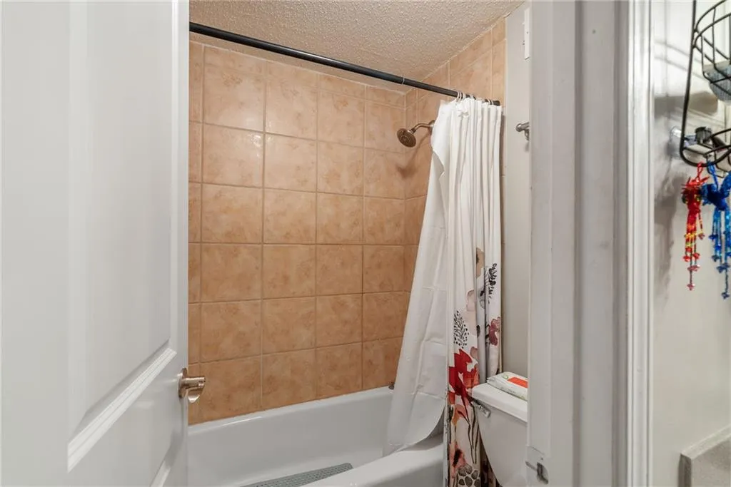 Bathroom with a textured ceiling and shower / bath combo