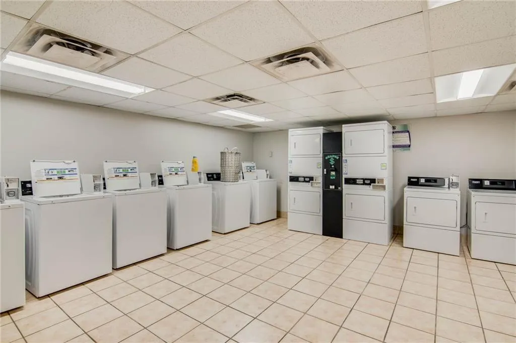 Laundry room featuring stacked washer and clothes dryer, washer and clothes dryer, and light tile flooring