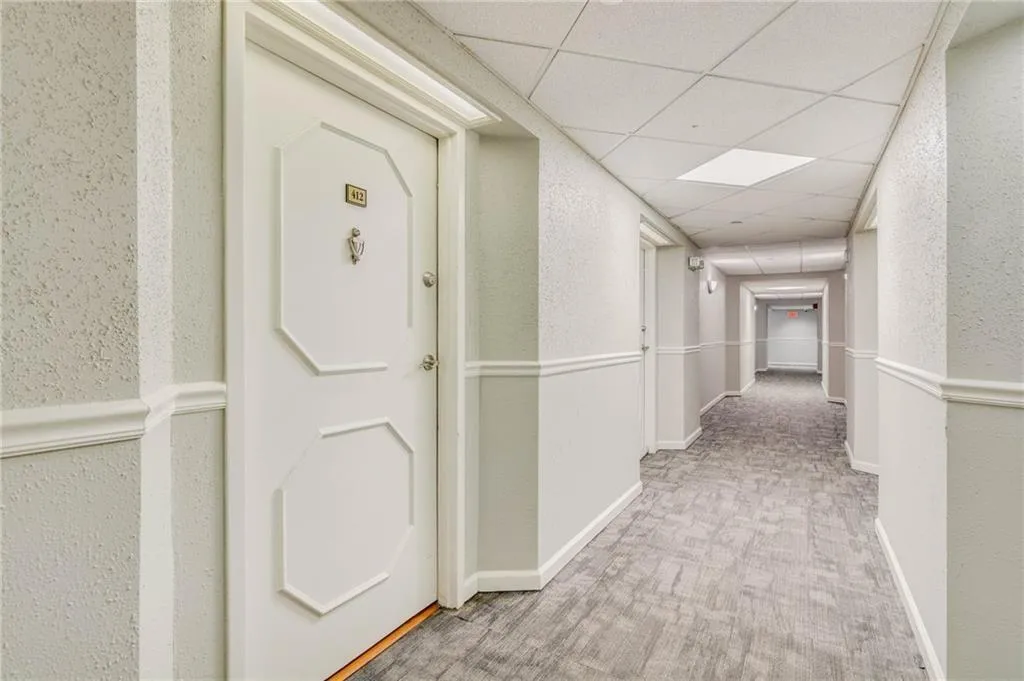 Hallway with light carpet and a drop ceiling