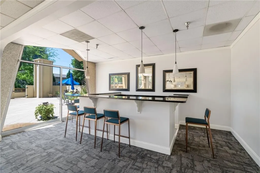 Kitchen featuring a drop ceiling, decorative light fixtures, a kitchen breakfast bar, and dark carpet