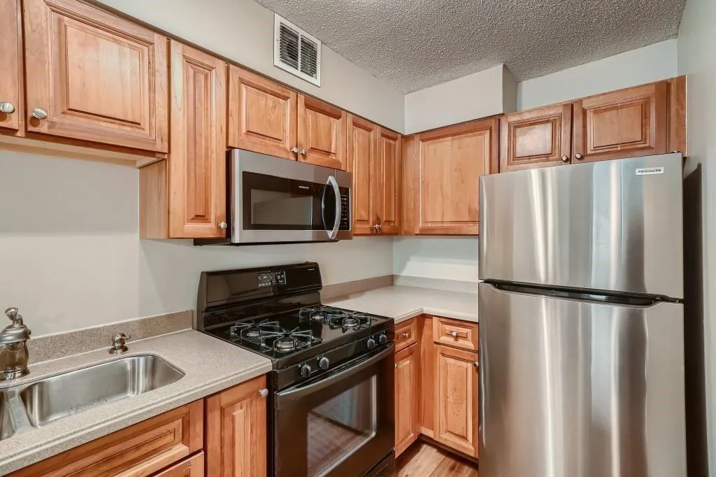 Kitchen featuring appliances with stainless steel finishes, a textured ceiling, sink, and light hardwood / wood-style floors