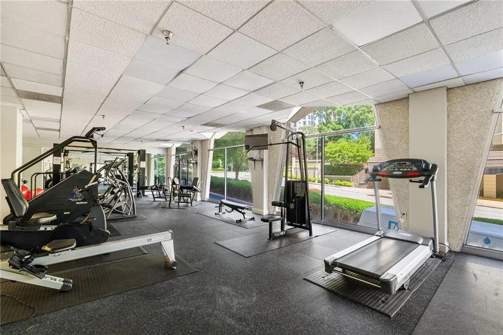 Gym with floor to ceiling windows and a drop ceiling