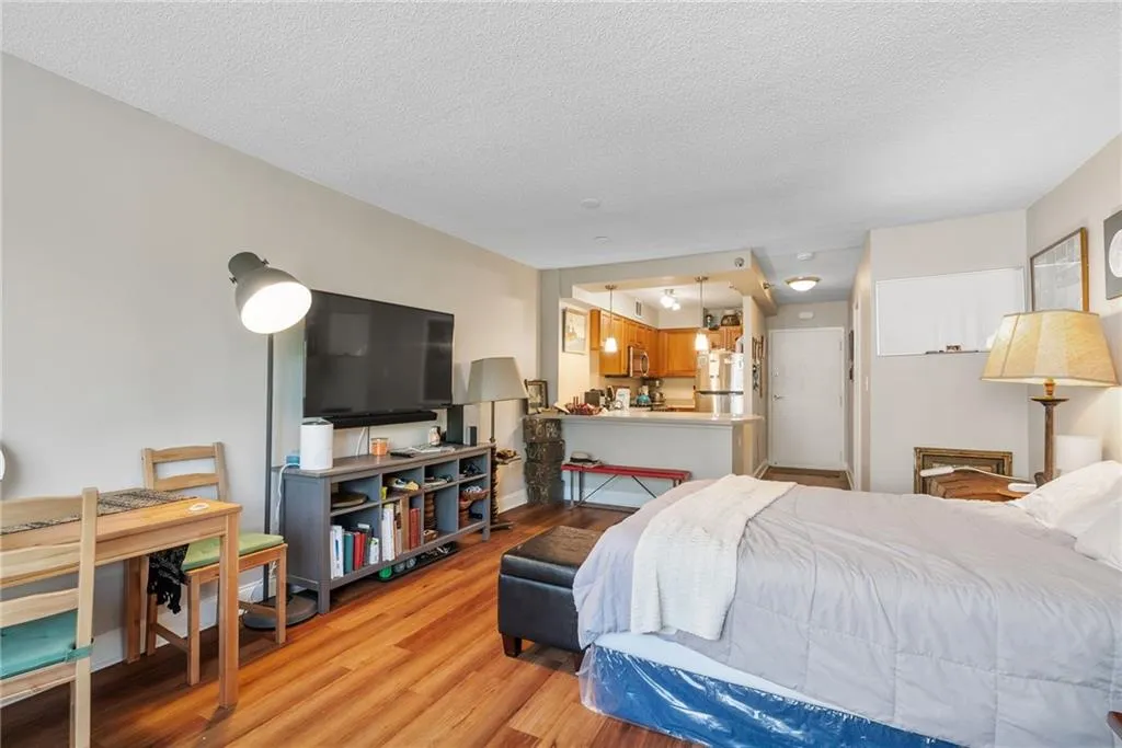 Bedroom featuring wood-type flooring, stainless steel refrigerator, and a textured ceiling