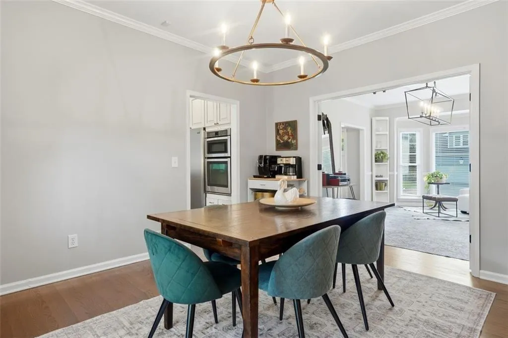 Spacious dining area featuring wood-finish flooring, an ornate chandelier, and an open doorway