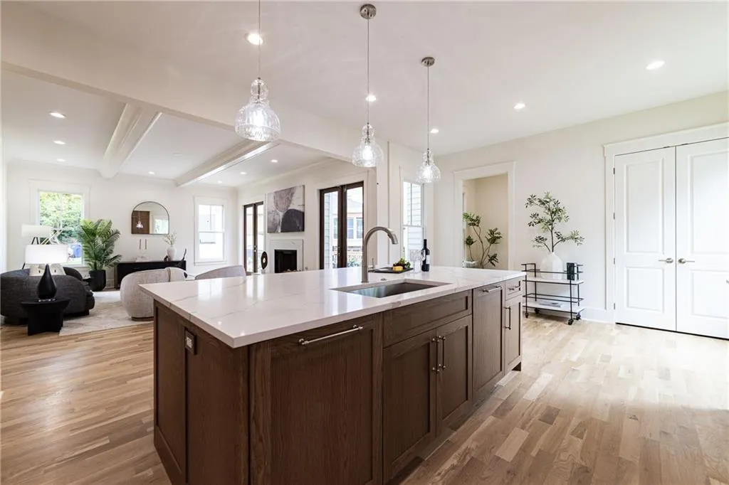 Kitchen with a sink, light wood-style floors, open floor plan, light stone counters, and a kitchen island with sink