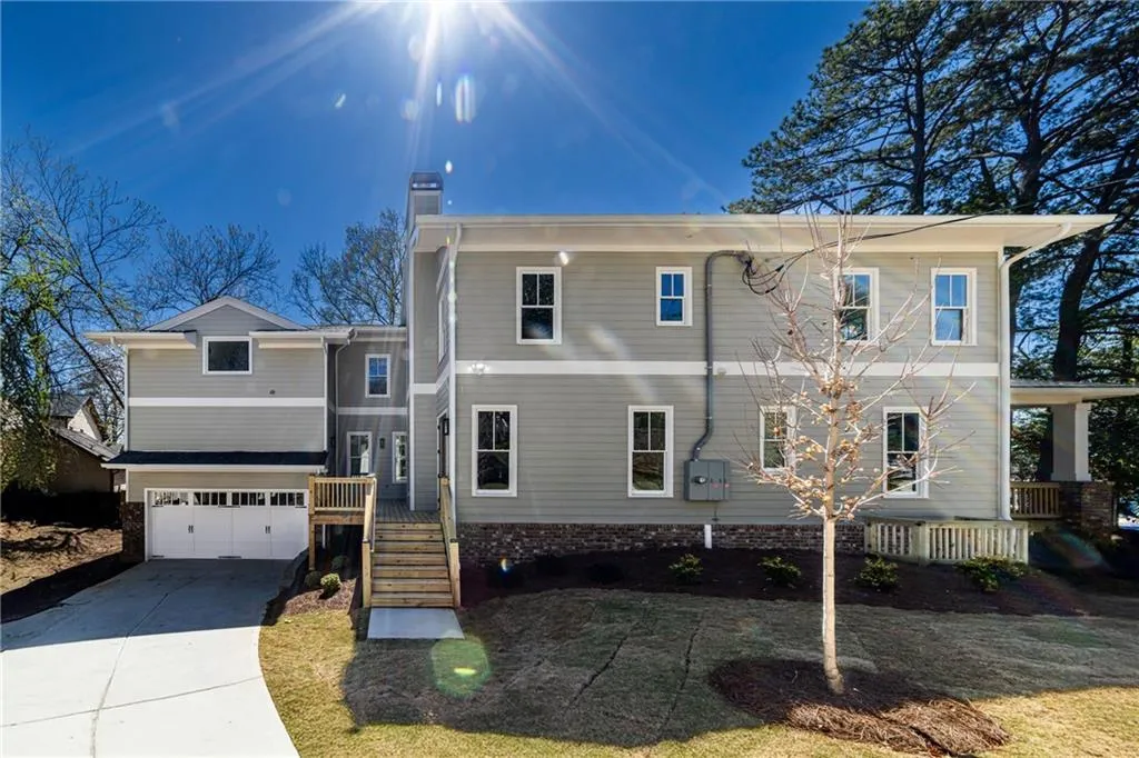 View of front facade with covered porch, driveway, an attached garage, and a chimney