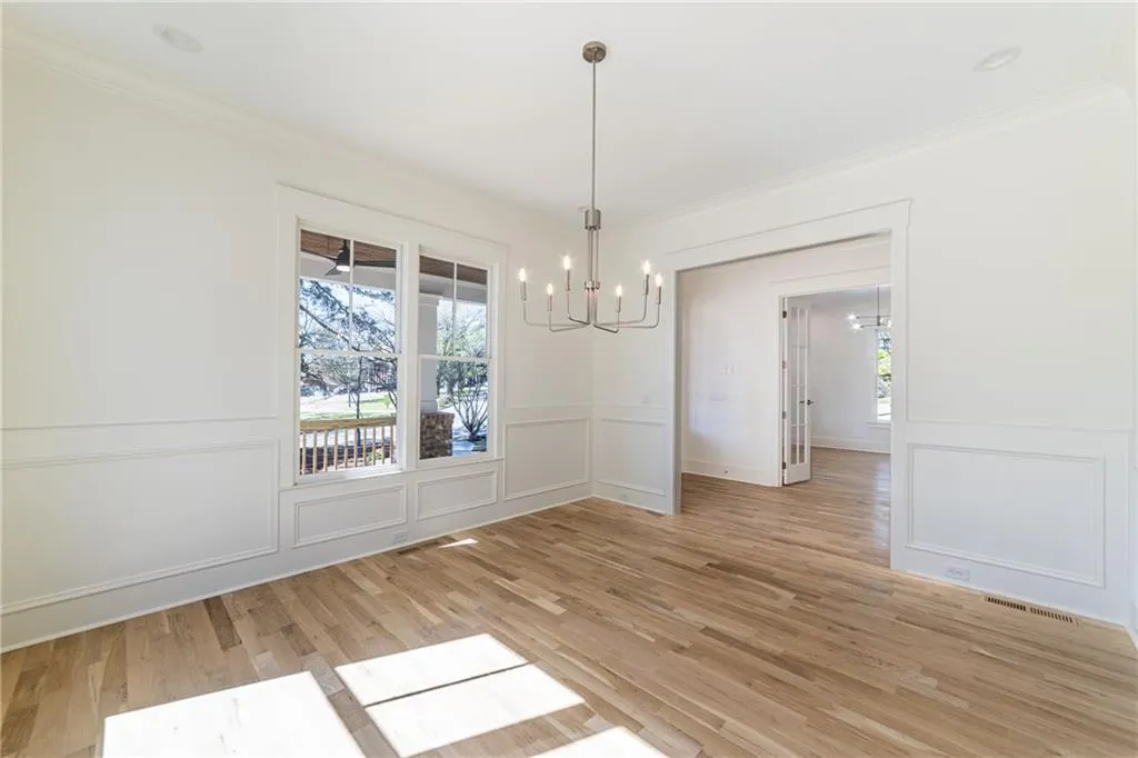Unfurnished dining area featuring a notable chandelier, visible vents, ornamental molding, and a decorative wall