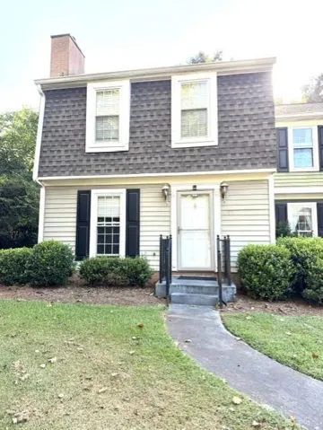 Two-story exterior with light-colored siding and a steep gambrel roof