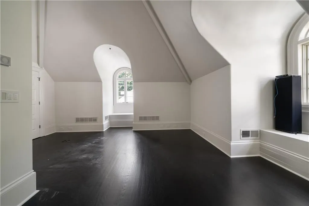 Additional living space with dark wood-type flooring and vaulted ceiling