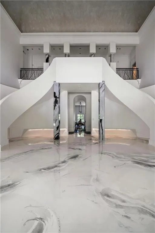 Foyer featuring ornamental molding, marble tiled flooring, stairway, and arched walkways