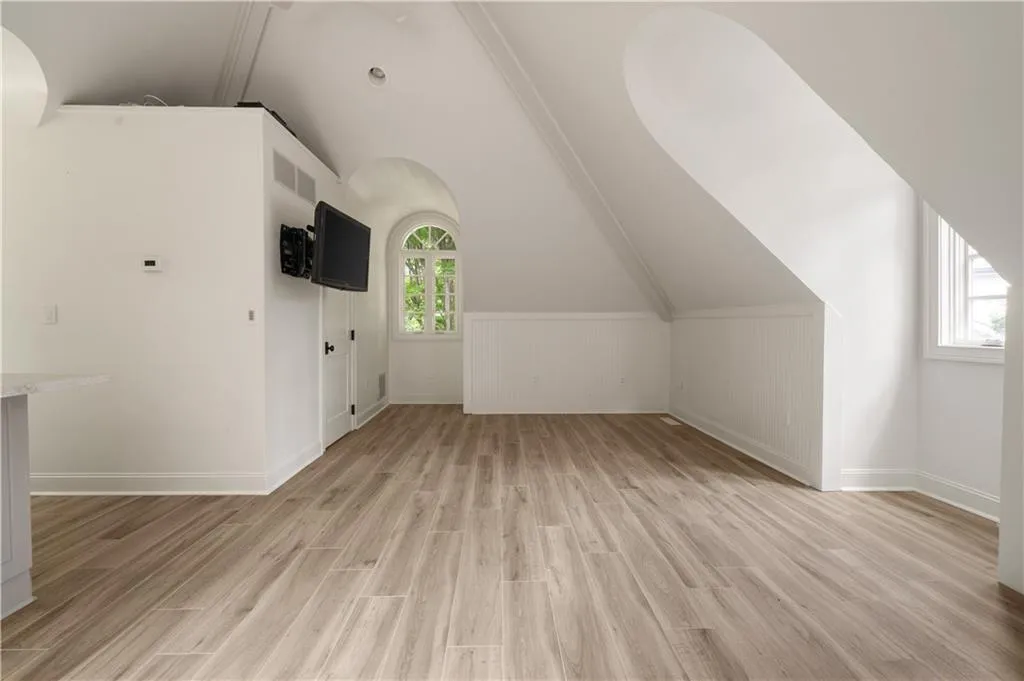 Bonus room featuring vaulted ceiling, light wood-style floors, plenty of natural light, and wainscoting