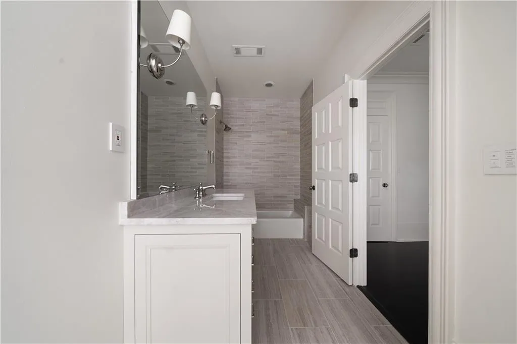 Full bath with vanity, wood tiled floors, and tiled shower / bath combo