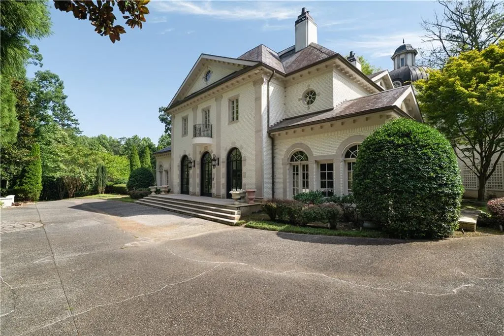 Greek revival inspired property with brick siding, a chimney, and a high end roof