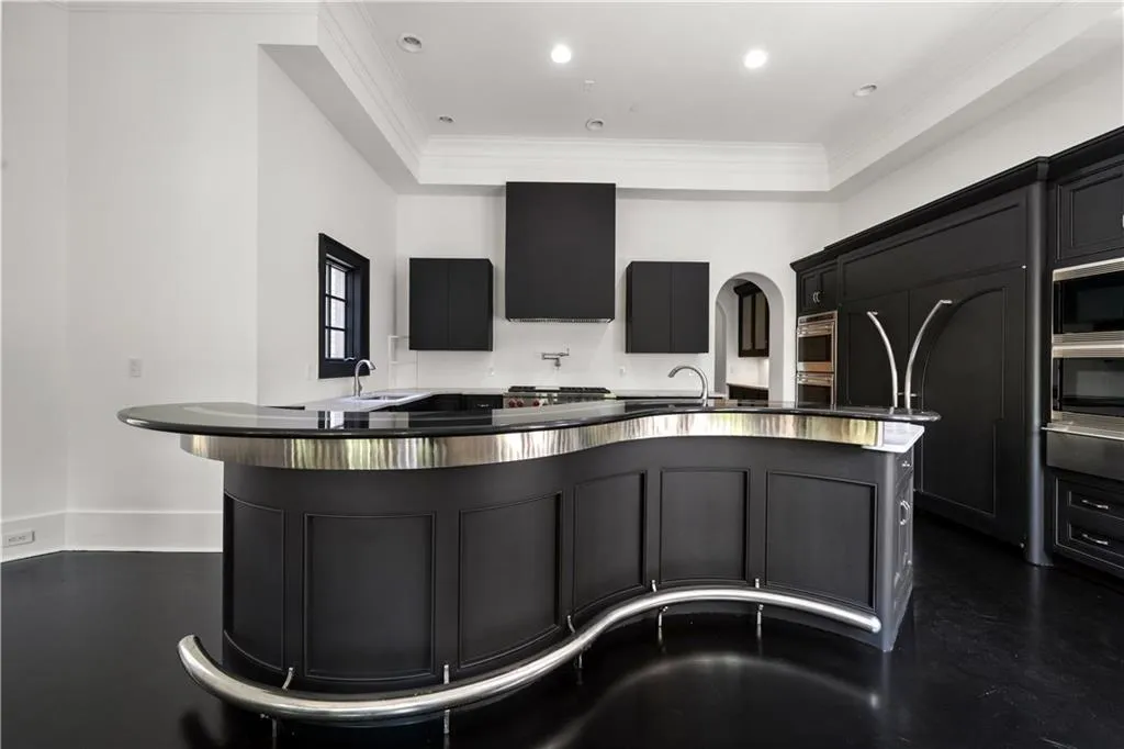 Kitchen featuring dark cabinets, a breakfast bar, ornamental molding, arched walkways, and stainless steel microwave