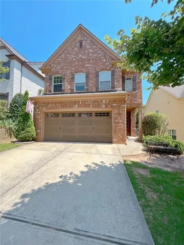 Brick facade residence featuring a two-car garage with panel doors, multi-paned windows with decorative shutters, a covered entry, and a concrete driveway