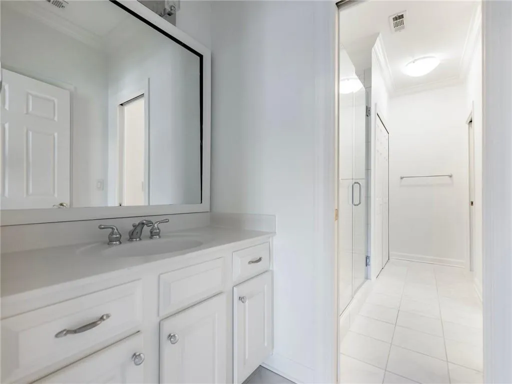 Bathroom featuring crown molding, walk in shower, tile patterned floors, and vanity.