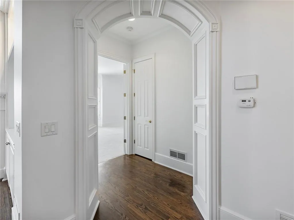 Corridor featuring ornamental molding and dark hardwood floors.