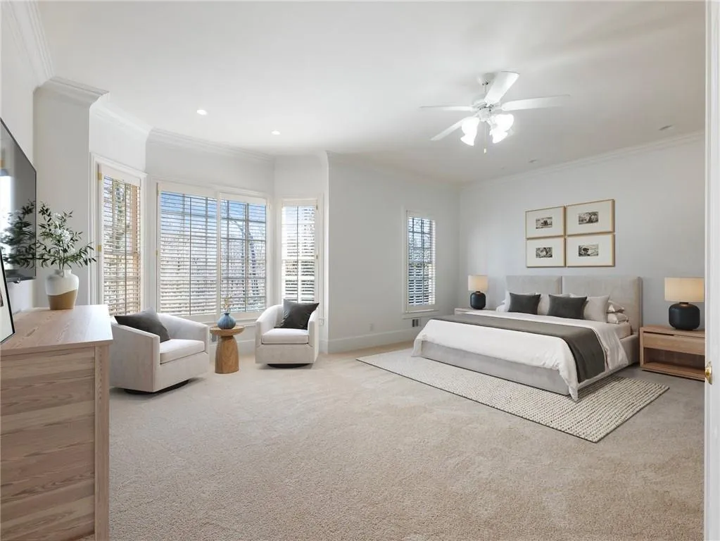 Carpeted bedroom featuring ceiling fan and ornamental molding