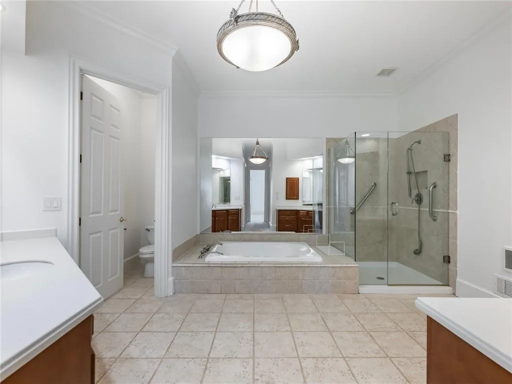 Full bathroom featuring tile patterned flooring, vanity, water closet, ornamental molding, and separate shower and tub.
