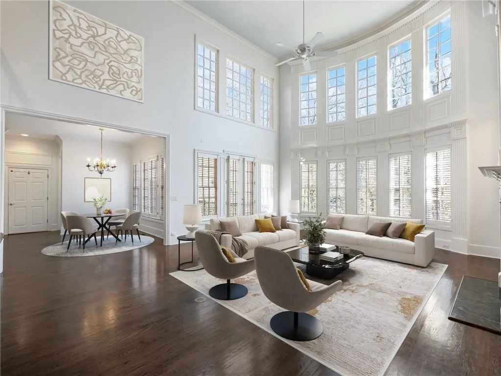Great room featuring a towering ceiling, ceiling fan with notable chandelier, ornamental molding, and hardwood flooring.