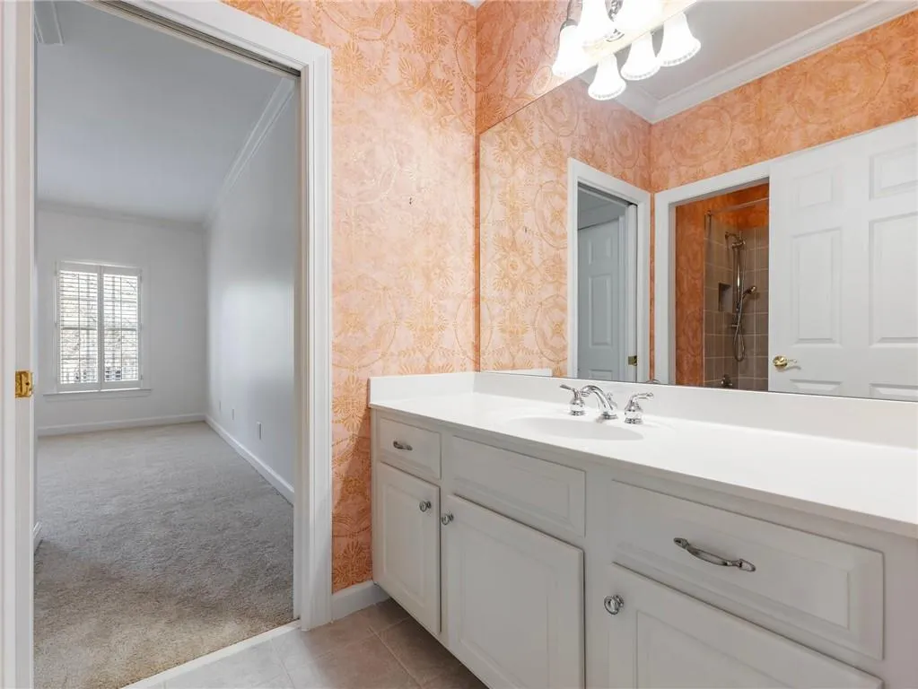Bathroom featuring vanity, crown molding, and tiled shower.
