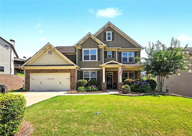 Two-story Colonial-style home featuring a brick and fiber cement exterior with complementary yellow trim, peaked gable rooflines, and multi-pane windows